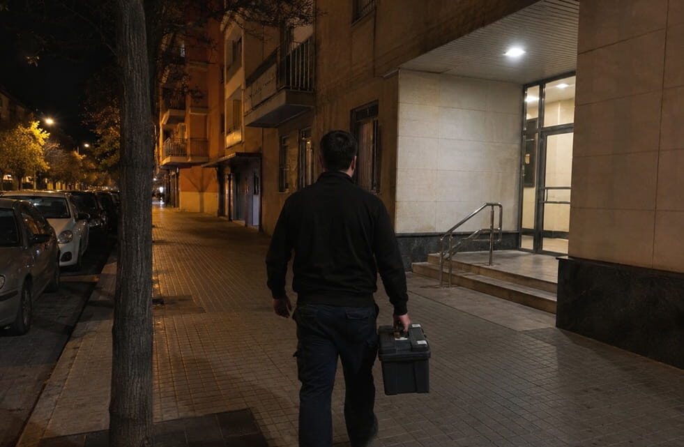 Técnico de espaldas caminando hacia portal iluminado de noche en Benicalap